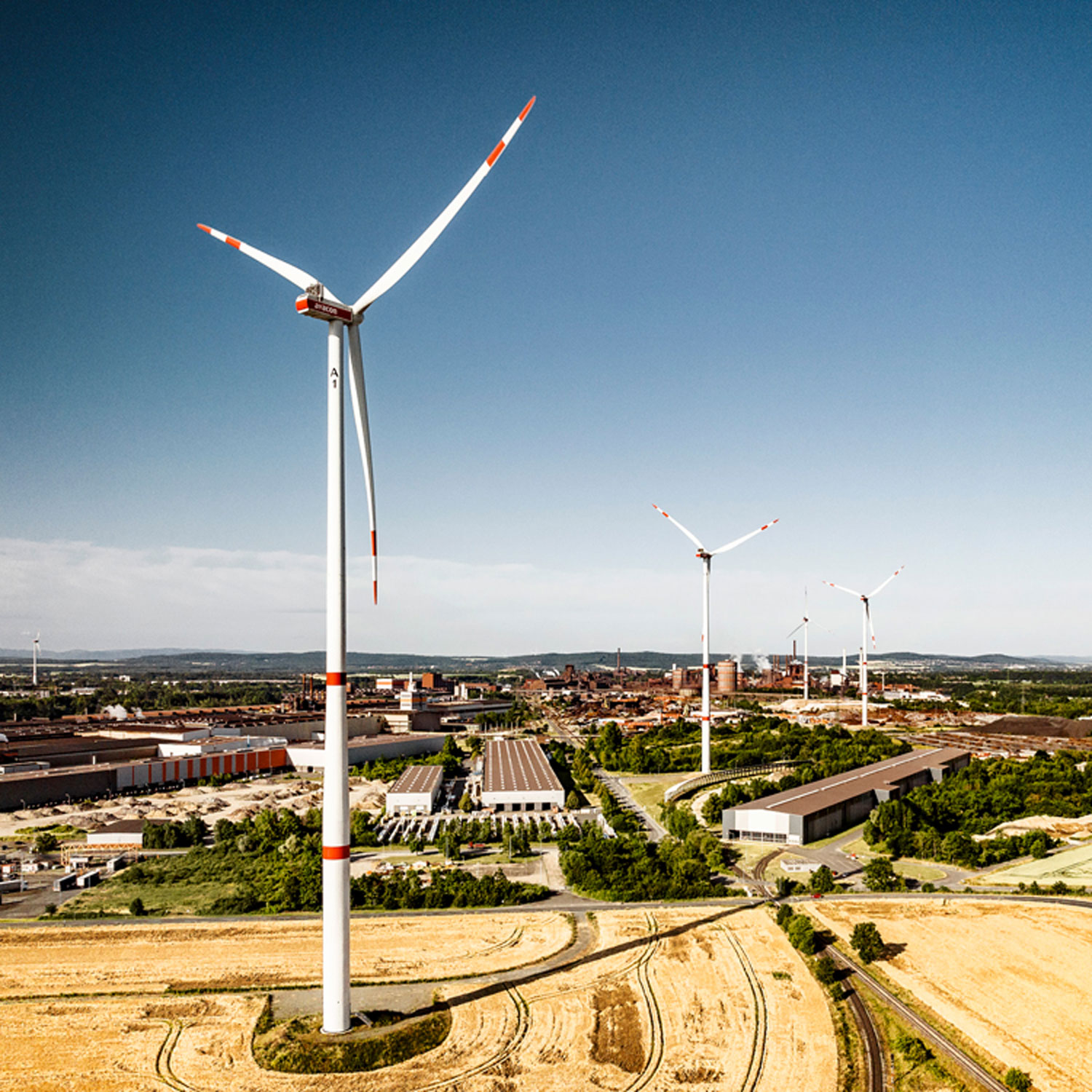 Windräder und Industrieanlage Windräder in einem Industriegebiet, erneuerbare Energiegewinnung durch Windkraft.