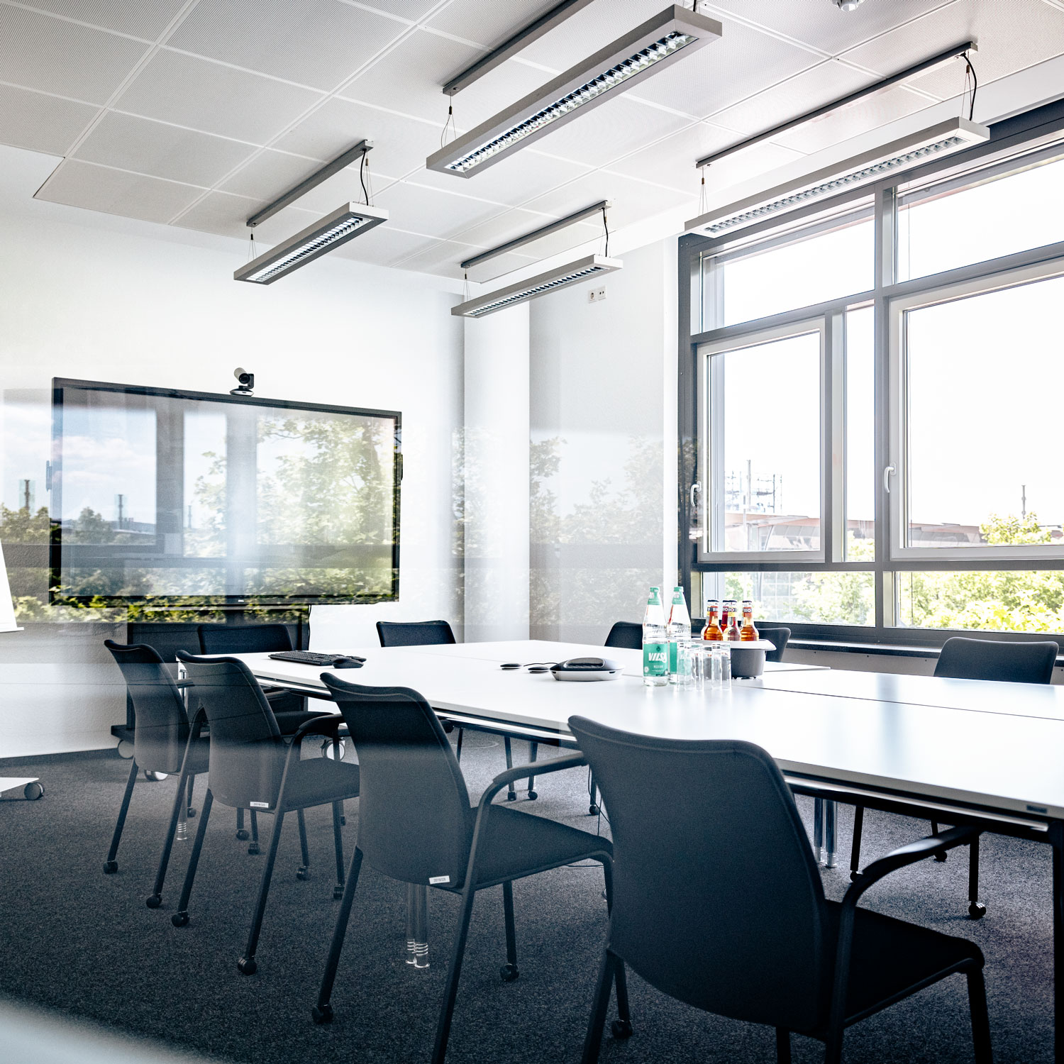 Konferenzraum mit Technologie und Tageslicht Moderner Konferenzraum mit technologischer Ausstattung, Tageslicht und Ausblick auf die Stadt.