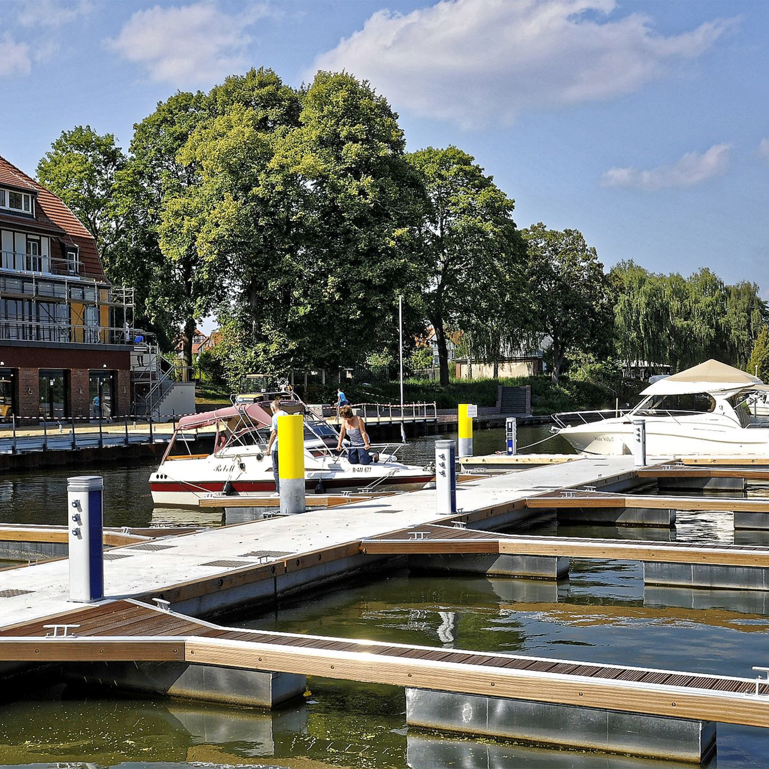 Steganlage Wildau Villa am See Aufnahme einer Marina am See mit Booten und Personen auf einer Steganlage.